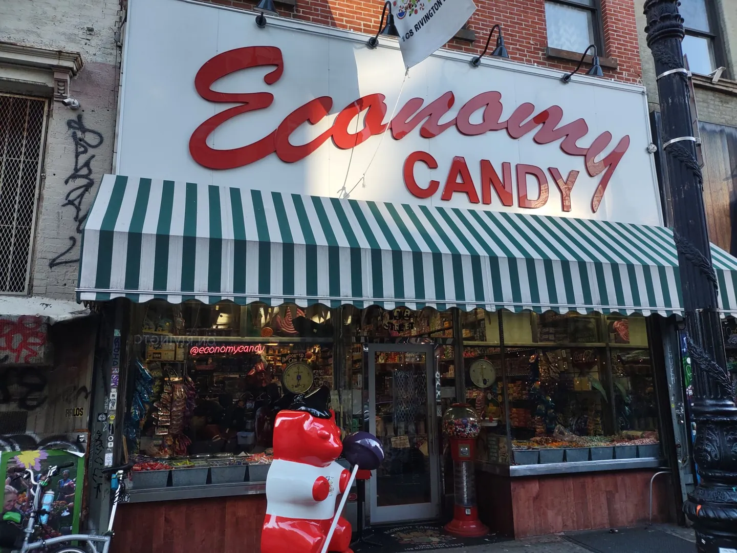 Economy Candy storefront with red script lettering, a striped green awning, and a window packed with candy