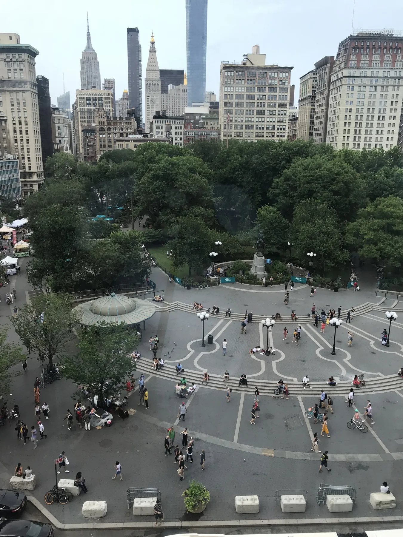 An elevated view of Union Square with pedestrians crossing patterned paving beneath a canopy of trees